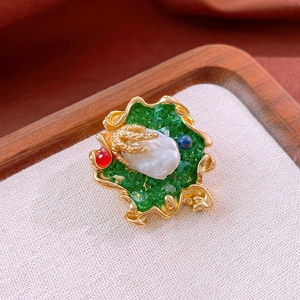 Close-up of vintage baroque pearl brooch with colorful gemstones and gold wavy edges