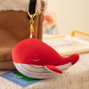 Cute red and white whale plush keychain hanging on a brown bag with gold lobster clasp