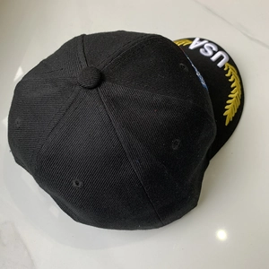 Vista detallada de una gorra de béisbol negra con bordado USA y hojas de laurel