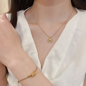 Detail der 18k vergoldeten Schaukelpferd-Halskette und Perlenarmband am Model