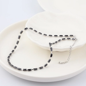 Detailed macro shot of a black rectangular zircon necklace with silver claw setting chain