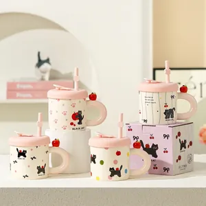 Close-up of cute ceramic cat mugs with pink lids, straws, and red apple details