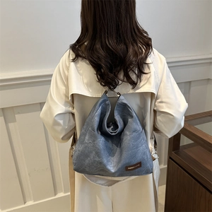 Blue denim tote bag showcased by model in stylish trench coat for casual commute look