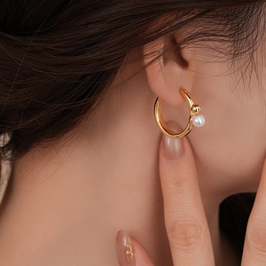 Gros plan sur une boucle d'oreille géométrique en or 14K avec perle sur un mannequin