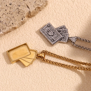Detail of 18K gold plated necklace and rhinestone poker card pendant on textured stone