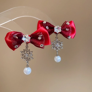 Close-up of red satin bow earrings with silver snowflakes and white pearls