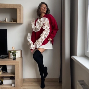 Détail d'un pull en maille rouge avec patchwork de volants blancs en forme de cœur