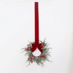 Detail of Christmas wreath with cypress branches, red berries and long velvet ribbon bow
