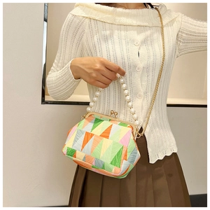 Detail of vibrant geometric patchwork shell bag with pearl handle and gold chain strap