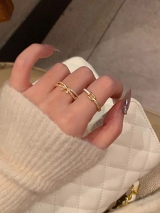 Detail of gold bow pearl and twisted rings worn by model against a white quilted bag