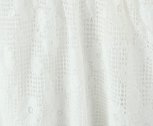 Gros plan sur la broderie florale en dentelle délicate de la robe courte blanche
