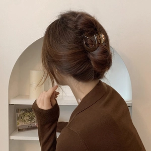 Brown amber resin hair claw clip worn by a model in a minimalist aesthetic setting
