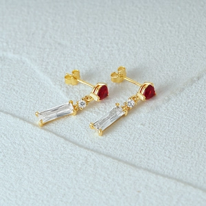 Detail of 18K gold earrings featuring red heart gems and transparent zircon drops