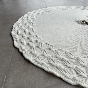 Detail of cream knit Christmas tree skirt with thick cable pattern and wavy edges