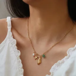 Gold ocean necklace with starfish, shell, pearl and green gemstone pendants on a model
