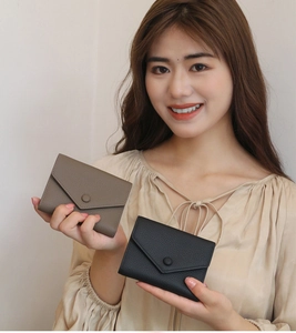 Slim genuine leather envelope wallet with litchi grain texture held by a female model