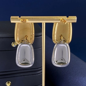 Titanium steel square tag earrings with two-tone gold and silver mirror finish on a stand