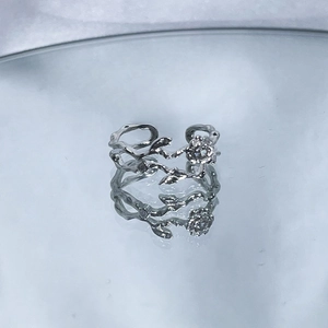 Detail view of irregular silver flower ring with crystal on reflective mirror surface
