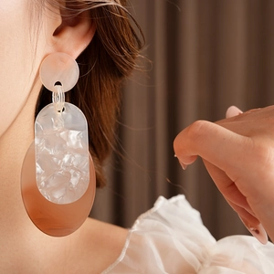 Close-up of geometric acrylic earrings with pink and peach translucent oval drops