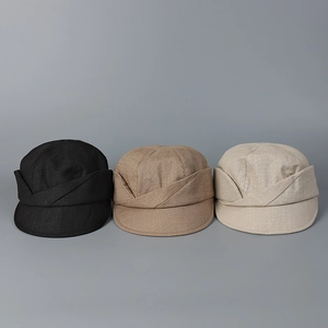 Texture detail of linen baker boy hats in black, khaki, and cream with cross-over design