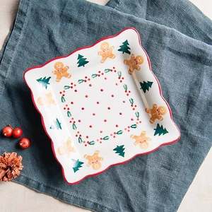 Close-up of square ceramic Christmas plate with wavy red edge and gingerbread man pattern
