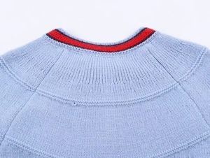 Detail of light blue knit cardigan with striped varsity neckline and raglan sleeves