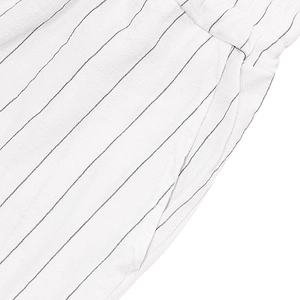 Detail of white linen beach shorts with black stripes showing seam and side pocket