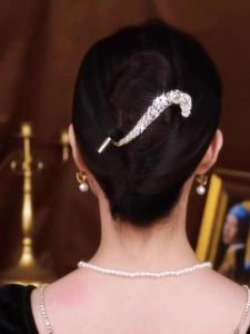 Detailed view of luxury rhinestone curved hair pin worn on a model's elegant hairstyle