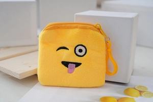 Detail of soft yellow plush coin purse with embroidered smile and plastic hook