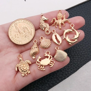 Golden sea creature charms set shown in hand with a coin for size comparison