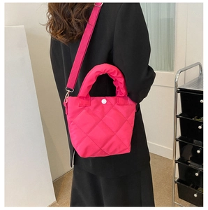Detail of magenta quilted handbag with diamond stitching and padded handle on a model