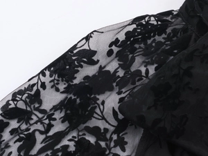 Detailed macro view of black mesh fabric with flocked floral texture for pleated dress