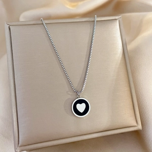 Macro detail of silver necklace with round heart pendant on golden box with silk