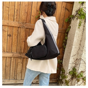 Detail view of black nylon shoulder bag with white stripes and small pouch on strap