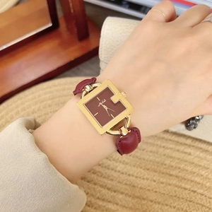 Elegant gold square quartz watch with burgundy leather strap on woman's wrist