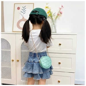Close-up of mint green round mini chain bag with heart-shaped quilted texture on child