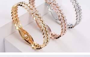 Three-tier display of gold, rose gold, and silver zigzag bangles with pavé crystal accents