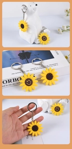 Detail of sunflower PVC keychain with a smiling face and metallic ring on a soft background