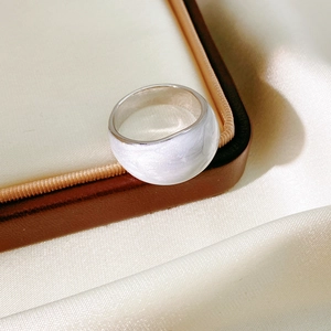 Macro view of wide silver ring featuring a polished white shell inlay on a silk background