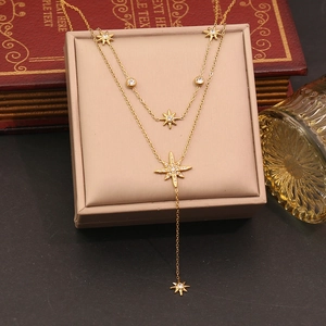 Detail of gold double-layered star pendant necklace displayed on a beige jewelry stand