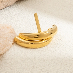 Detail of 18K gold-plated U-shaped chunky earring on a minimalist stone background