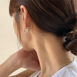 Polished silver U-shaped horseshoe earrings shown on model for style and scale