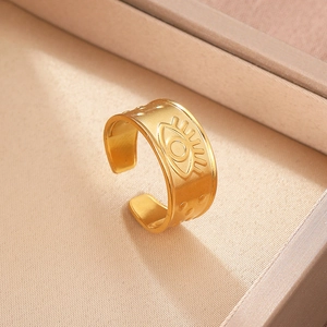 Macro shot of gold-plated stainless steel wide band ring featuring embossed evil eye detail