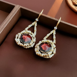 Detailed macro of vintage gold earrings with red round crystals and white baguette stones