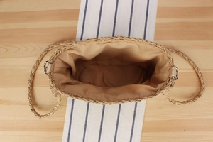 Détail du sac cabas en paille tissée avec doublure marron et finitions métalliques