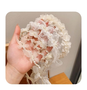 Close-up of white lace headband featuring delicate faux pearls and floral details