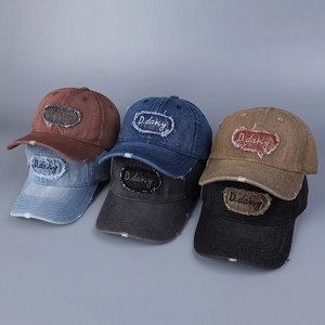 Dettaglio di cappelli da baseball in denim lavato con ricami effetto consumato vari colori