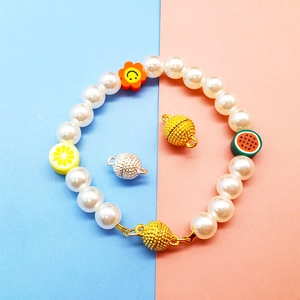 Detail of pearl bracelet with fruit charms and golden magnetic heart clasps