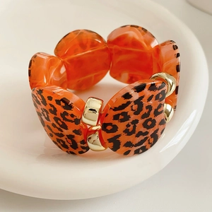 Close-up of leopard print resin pieces with gold metal buckles on a chic stretch bracelet