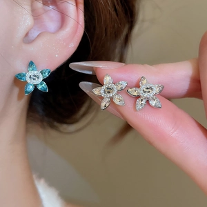 Macro shot of a flower stud earring with blue marquise crystals and center logo